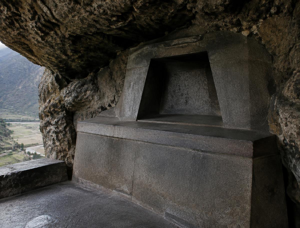 A precisely carved stone altar with a trapezoidal niche inside a rock overhang at Ñaupa Iglesia